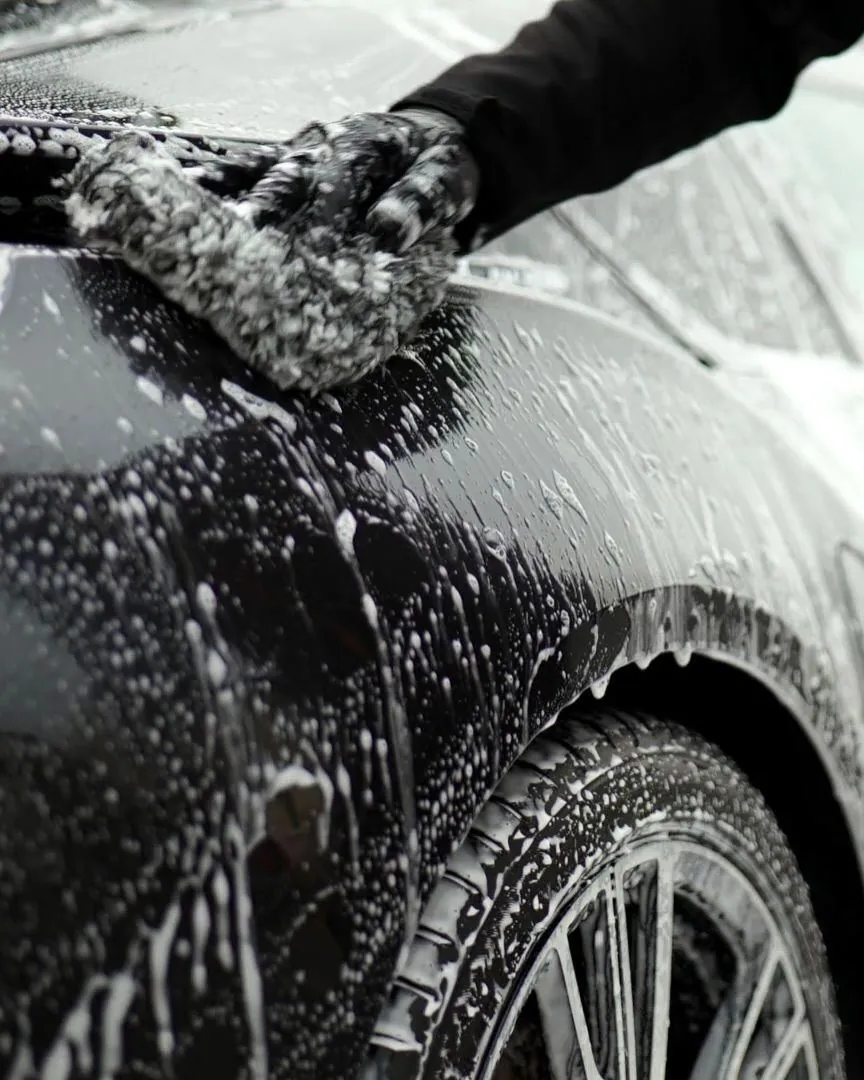 Lavado con espuma y guante de microfibra sobre auto negro